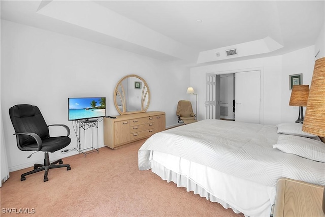 bedroom with a tray ceiling, a closet, and light colored carpet