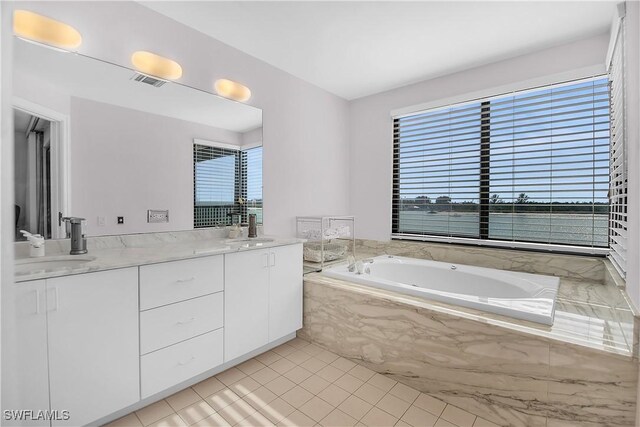 bathroom featuring tile patterned floors, vanity, a relaxing tiled tub, and a water view