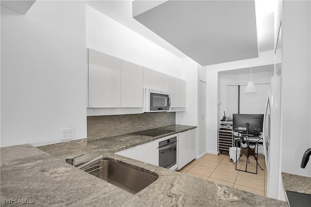 kitchen with light tile patterned floors, tasteful backsplash, oven, decorative light fixtures, and white cabinets