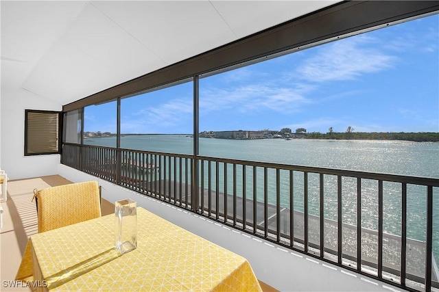 sunroom featuring a view of the beach, a water view, and lofted ceiling