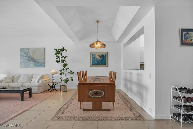 dining room featuring a tray ceiling and light tile patterned flooring