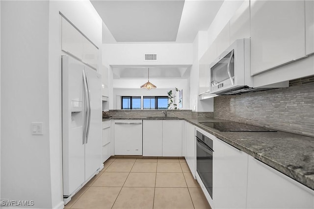 kitchen featuring white appliances, white cabinets, sink, light tile patterned floors, and decorative light fixtures