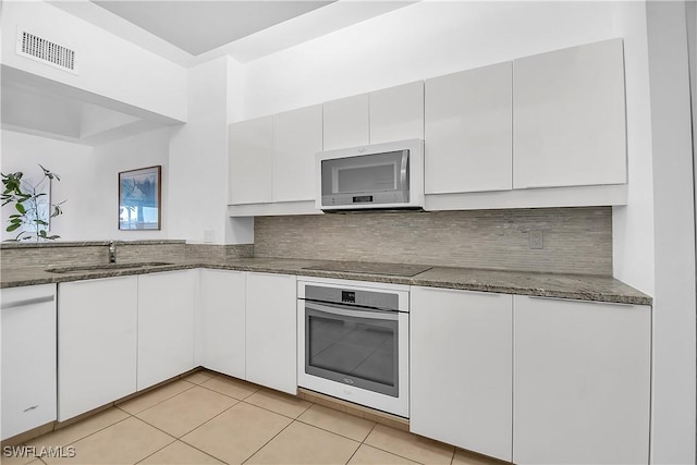 kitchen featuring white cabinetry, oven, decorative backsplash, black electric stovetop, and light tile patterned floors