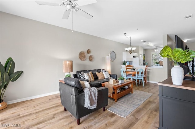 living room with light hardwood / wood-style floors and ceiling fan with notable chandelier