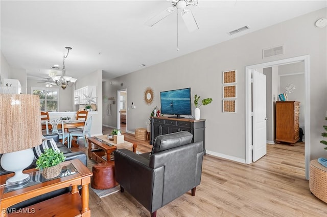 living room featuring light wood-type flooring and ceiling fan with notable chandelier