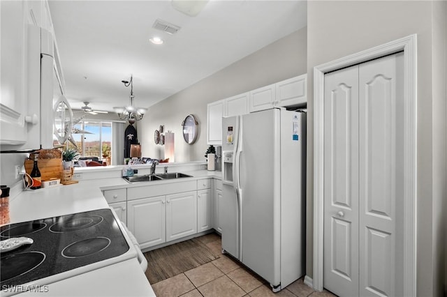 kitchen featuring kitchen peninsula, sink, white fridge with ice dispenser, and pendant lighting