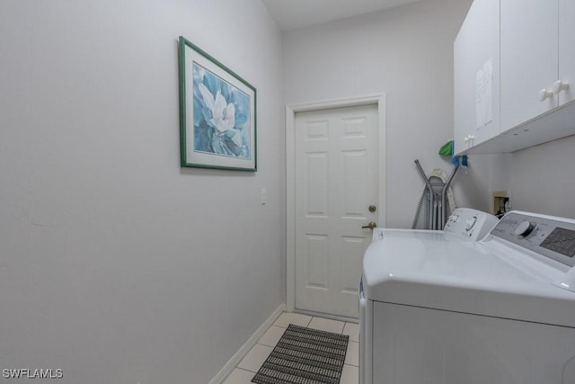 clothes washing area featuring washer and clothes dryer, light tile patterned floors, and cabinets