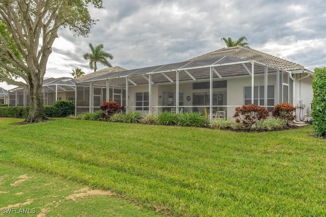 back of property featuring a yard and glass enclosure