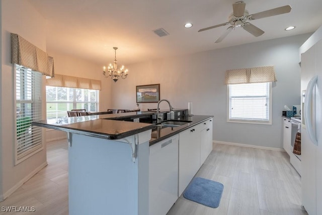 kitchen featuring ceiling fan with notable chandelier, sink, decorative light fixtures, white cabinetry, and a breakfast bar area