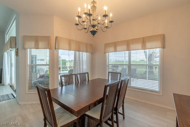 dining space featuring light wood-type flooring, a wealth of natural light, and a chandelier