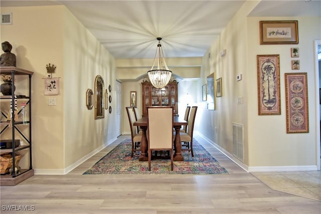 dining area featuring light wood-type flooring and an inviting chandelier