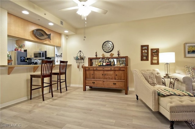 living area with ceiling fan and light hardwood / wood-style flooring