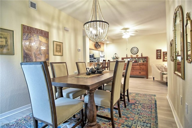 dining room with ceiling fan with notable chandelier and light wood-type flooring