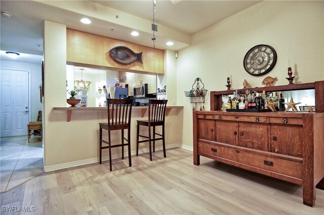 bar featuring light hardwood / wood-style floors and a chandelier