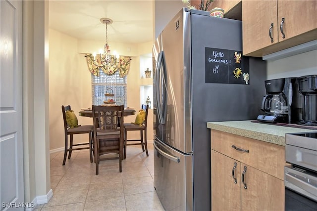 kitchen with light brown cabinetry, light tile patterned floors, a chandelier, stainless steel refrigerator, and hanging light fixtures