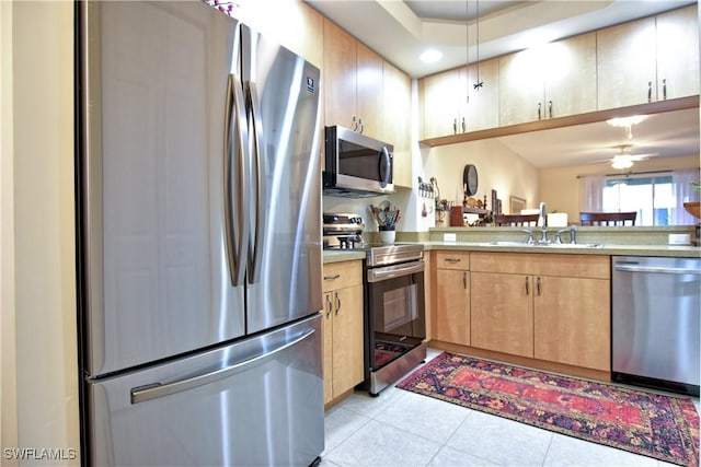 kitchen featuring a raised ceiling, sink, ceiling fan, light brown cabinetry, and appliances with stainless steel finishes