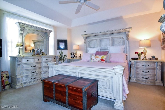 bedroom with a tray ceiling, ceiling fan, and carpet flooring