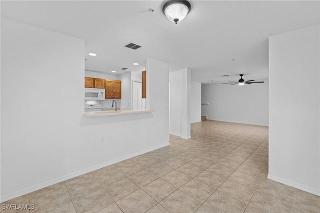 unfurnished living room with ceiling fan, sink, and light tile patterned floors