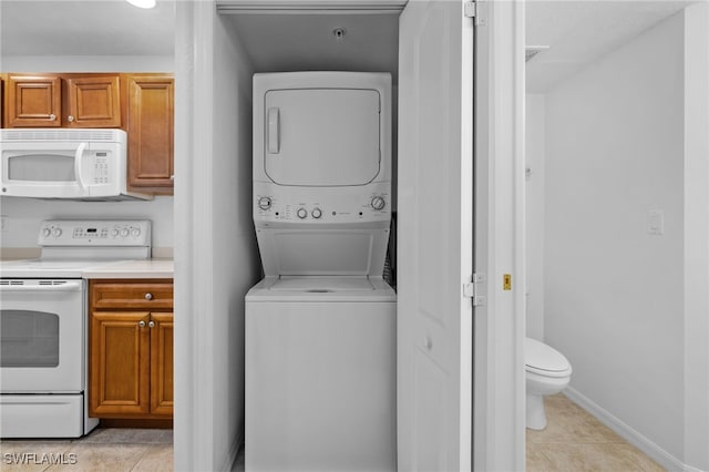 clothes washing area with light tile patterned floors and stacked washing maching and dryer