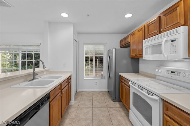 kitchen with light tile patterned floors, appliances with stainless steel finishes, brown cabinets, light countertops, and a sink