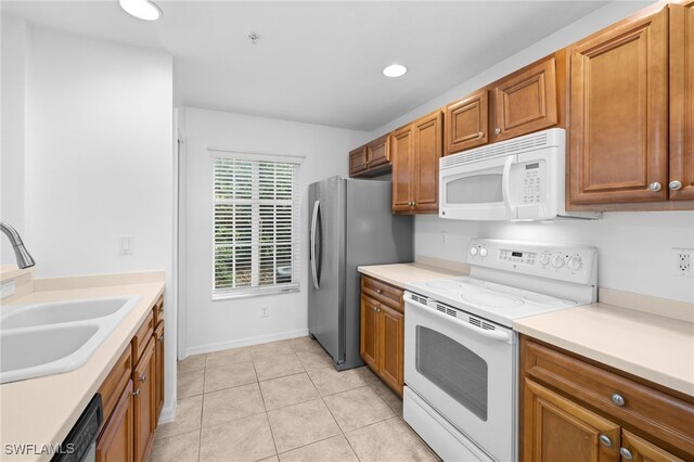 kitchen featuring sink, light tile patterned floors, and white appliances