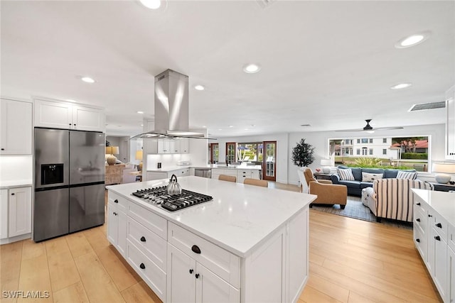 kitchen with light countertops, appliances with stainless steel finishes, light wood-style flooring, and island range hood