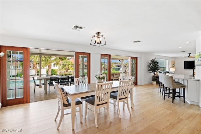 dining space with light wood-style flooring, visible vents, baseboards, and french doors