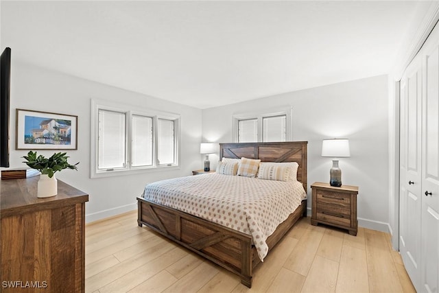 bedroom with light wood-style floors, baseboards, and a closet