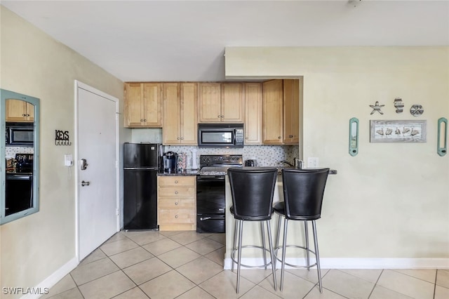 kitchen with decorative backsplash, a breakfast bar, black appliances, light brown cabinets, and light tile patterned flooring