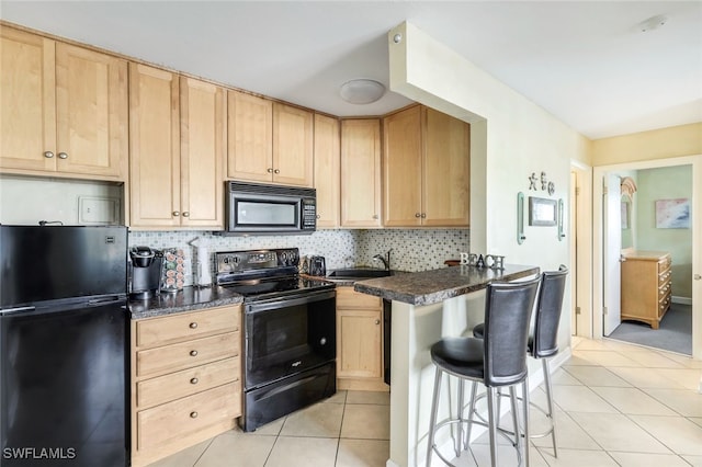 kitchen with light brown cabinets, black appliances, a kitchen breakfast bar, tasteful backsplash, and light tile patterned flooring