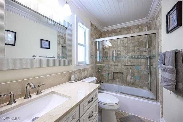 full bathroom with tile patterned floors, bath / shower combo with glass door, vanity, crown molding, and toilet