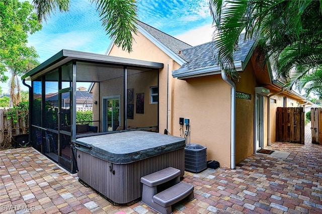 view of patio / terrace with a hot tub and a sunroom