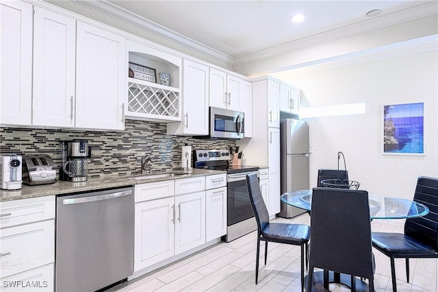 kitchen featuring white cabinets, sink, crown molding, light stone counters, and stainless steel appliances