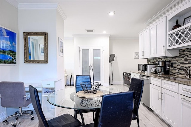 dining space with sink, light wood-type flooring, and ornamental molding