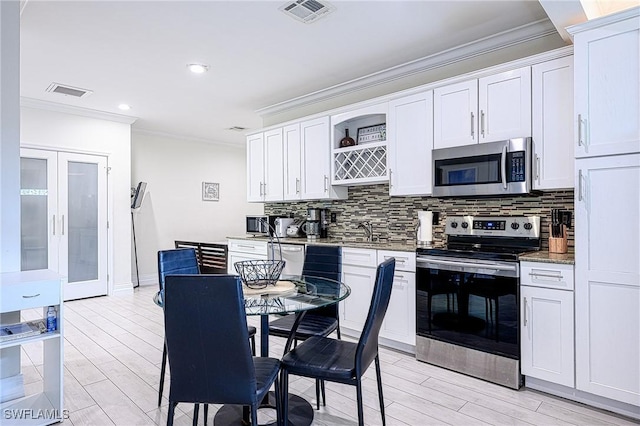 kitchen with appliances with stainless steel finishes, backsplash, light stone counters, sink, and white cabinetry