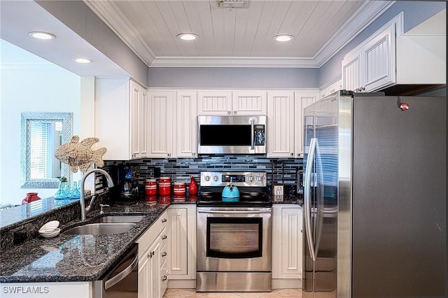 kitchen featuring appliances with stainless steel finishes, crown molding, sink, dark stone countertops, and white cabinets