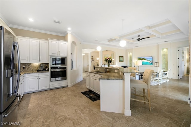 kitchen with white cabinets, dark stone countertops, a kitchen bar, and stainless steel appliances