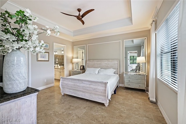 bedroom featuring ceiling fan, a raised ceiling, ornamental molding, and connected bathroom