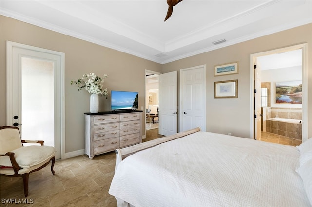 bedroom featuring a tray ceiling, ensuite bath, ceiling fan, and ornamental molding