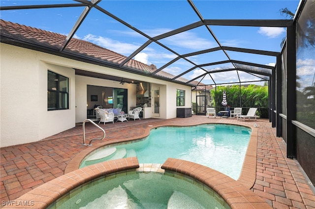 view of pool featuring glass enclosure, an in ground hot tub, ceiling fan, and a patio