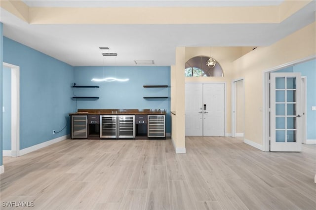 interior space featuring wine cooler, pendant lighting, and light hardwood / wood-style floors