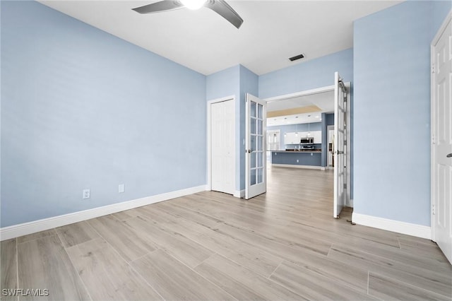 spare room featuring french doors, light wood-type flooring, and ceiling fan