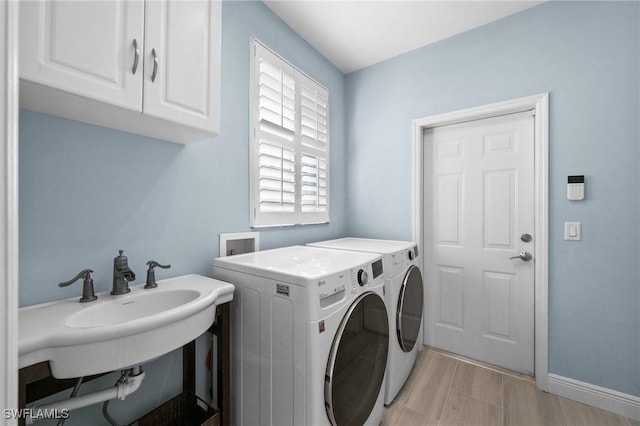 washroom featuring cabinets, washing machine and dryer, light hardwood / wood-style floors, and sink