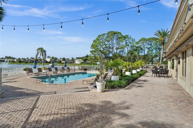 view of swimming pool featuring a water view and a patio