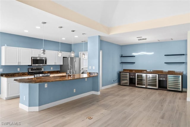 kitchen featuring white cabinetry, hanging light fixtures, beverage cooler, and appliances with stainless steel finishes