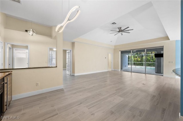 unfurnished living room with light hardwood / wood-style floors, a raised ceiling, and ceiling fan