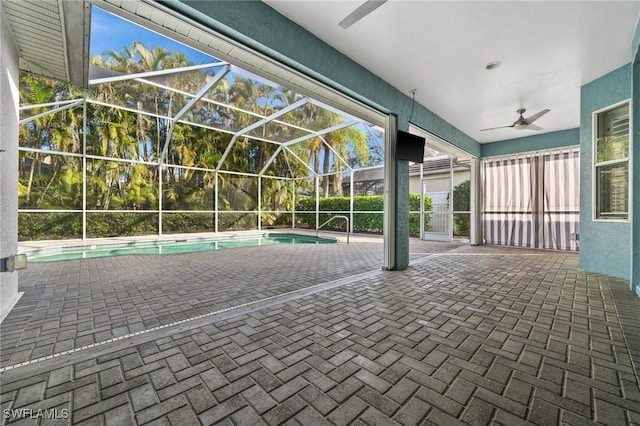 view of swimming pool with a patio area, ceiling fan, and glass enclosure