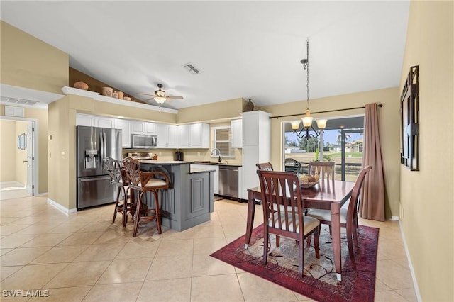 dining space with vaulted ceiling, sink, light tile patterned flooring, and ceiling fan with notable chandelier