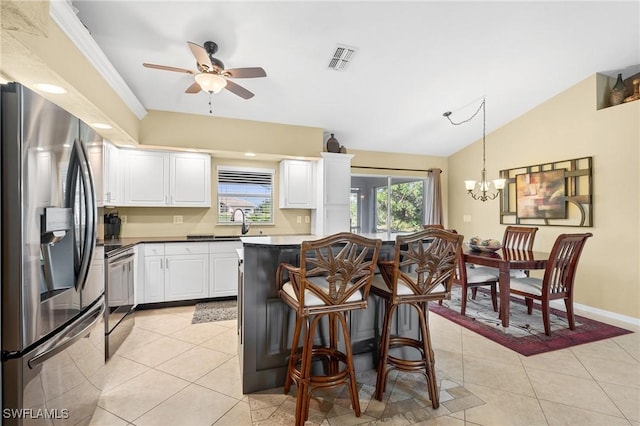 kitchen featuring appliances with stainless steel finishes, light tile patterned floors, decorative light fixtures, white cabinets, and lofted ceiling