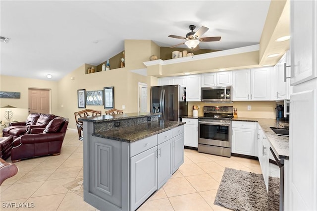 kitchen with appliances with stainless steel finishes, dark stone counters, ceiling fan, light tile patterned floors, and white cabinets